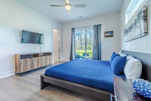 Ein Schlafzimmer mit einem Bett, einem Fernseher, einem Holzschrank und einem Fenster mit Vorhängen.