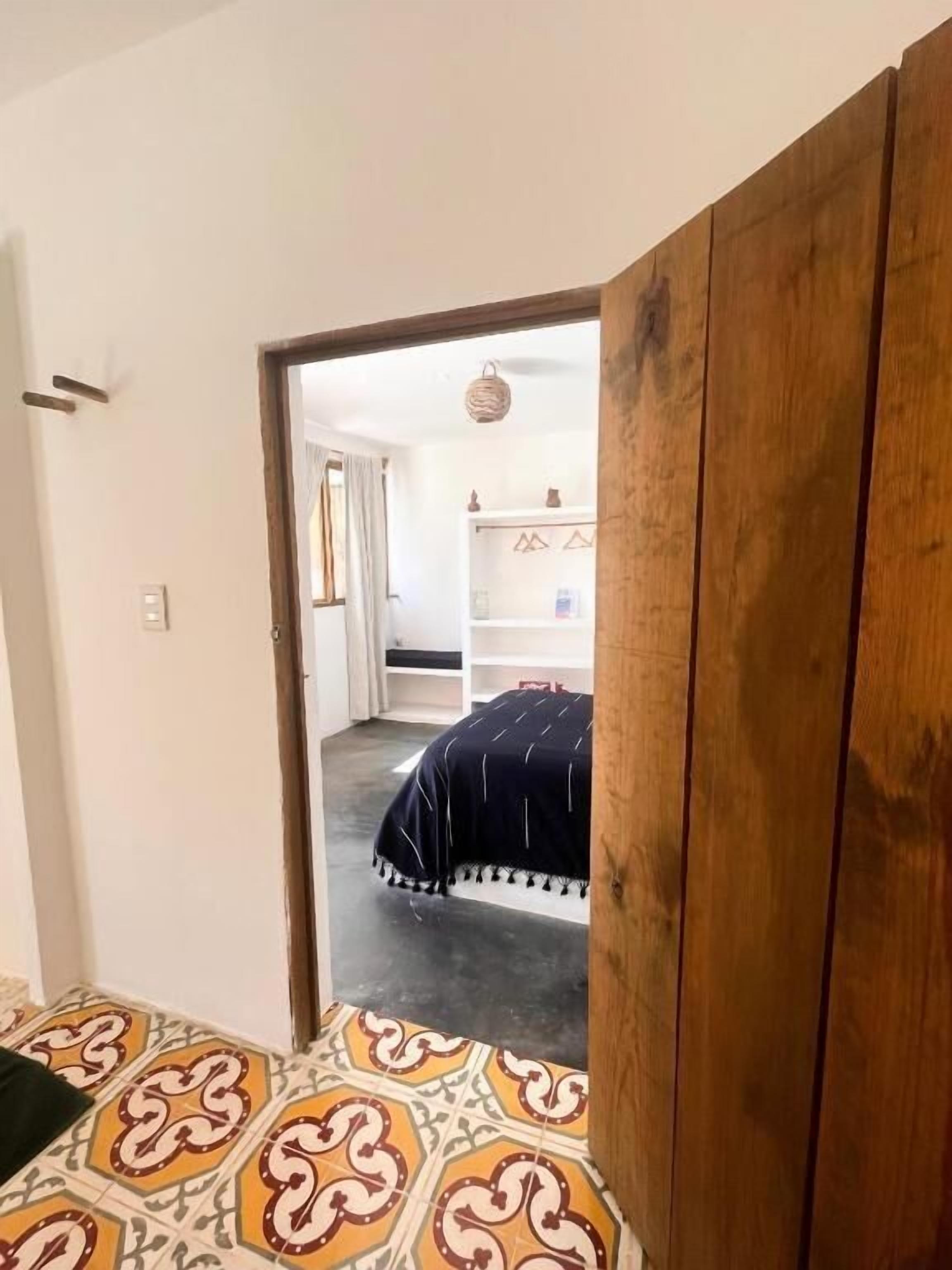Una habitación con una cama, un armario de madera y un pasillo que conduce a un baño.
