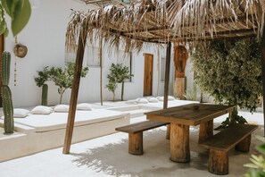 A patio with a wooden table and benches, surrounded by cacti and plants. - Villa Leone Privatisée (Brisas de Zicatela)