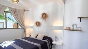 A bedroom with a bed, a ceiling fan, a window with curtains, and a shelf with items. - Villa Leone Privatisée (Brisas de Zicatela)