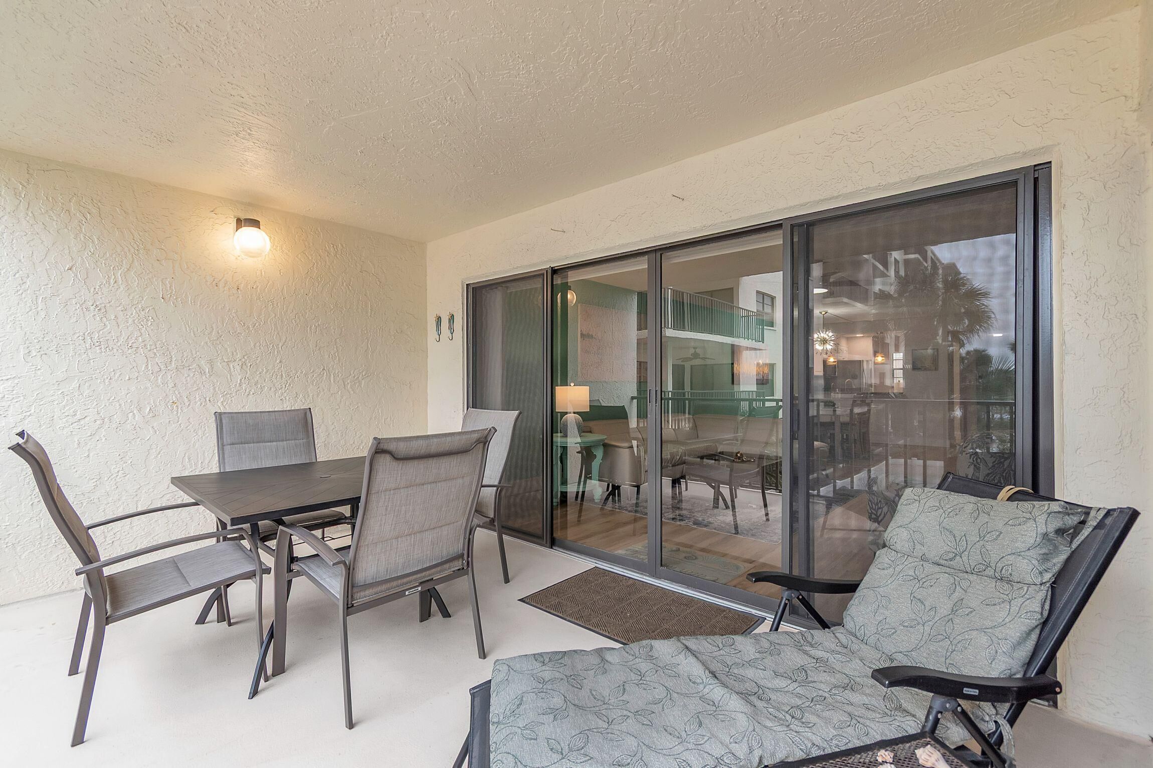 A balcony with a table and chairs, a sliding glass door, and a view of the interior.