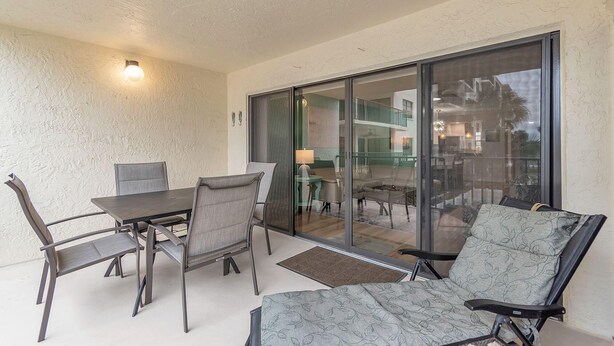 Een balkon met een tafel en stoelen, een schuifdeur en uitzicht op het interieur.