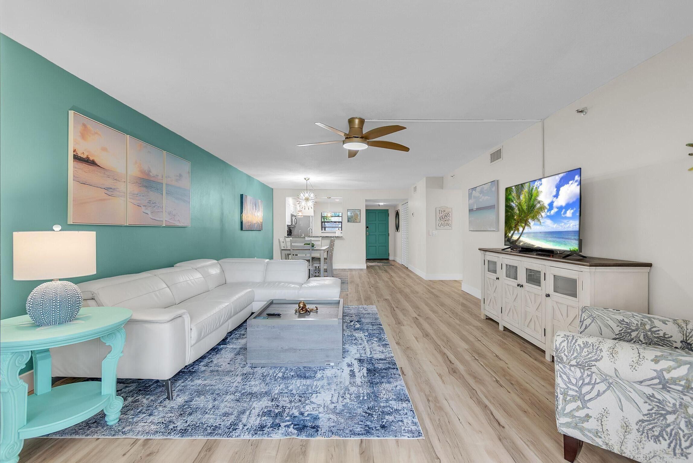 A living room with a white sofa, a coffee table, a TV, and a ceiling fan.