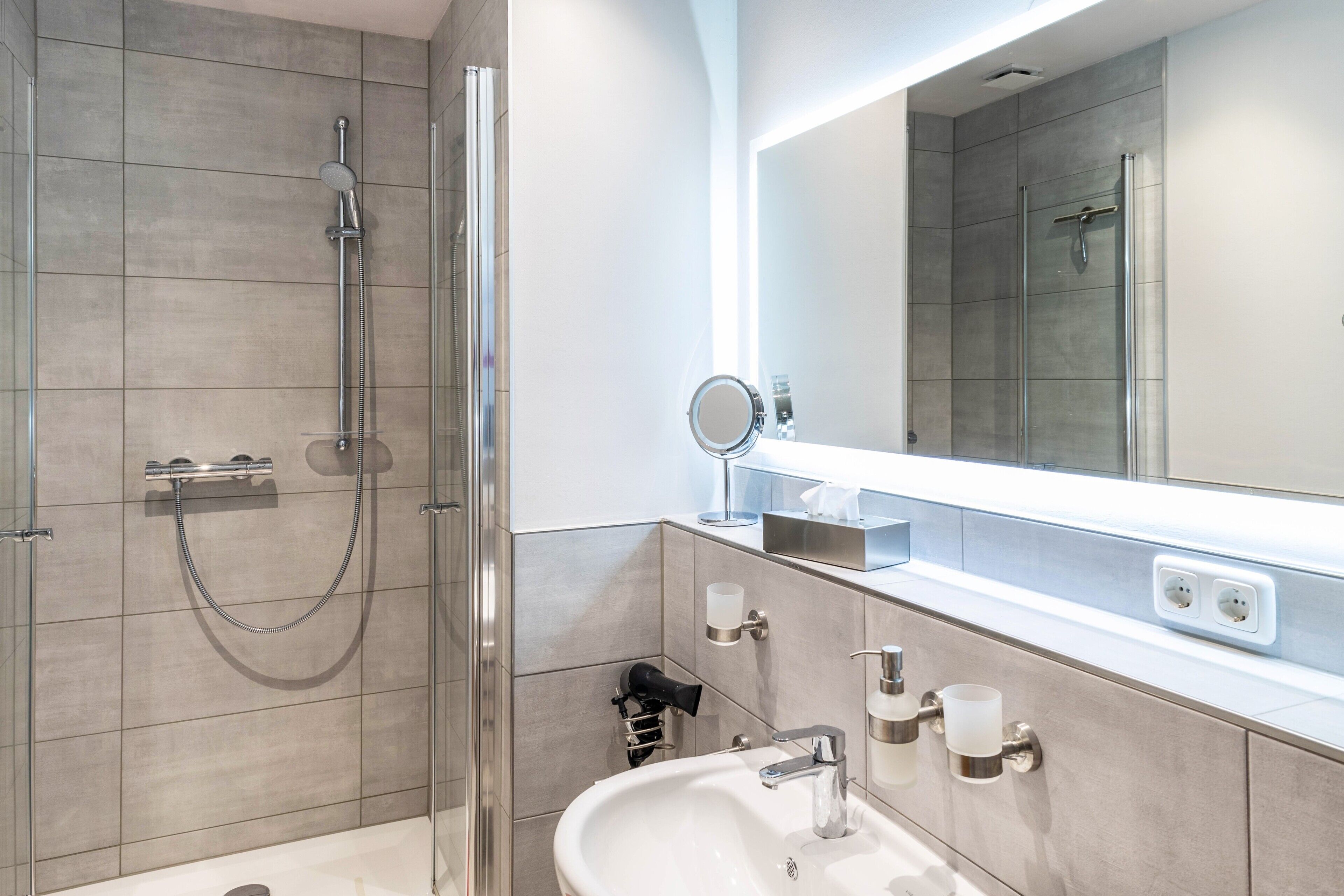 Un bagno moderno con doccia a vetro, lavandino con specchio e porta asciugamani.