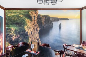 Comedor con una mesa, sillas y vista a un acantilado y al mar.