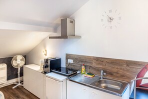 A modern kitchen with a built-in stove, a sink, and a clock on the wall. - Apartment 'Above the Pub' with Wi-Fi and Air Conditioning (Michendorf)