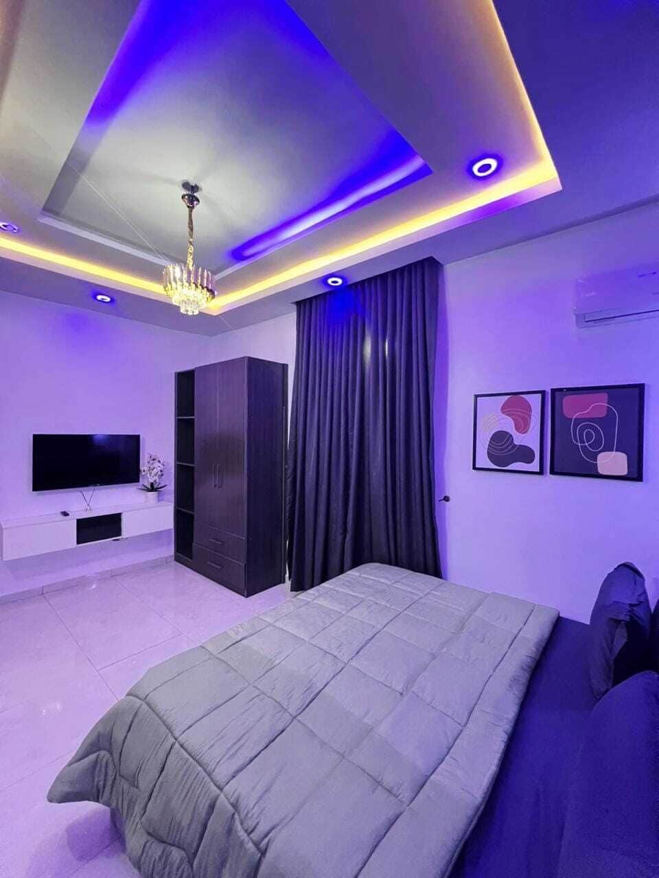 Een moderne slaapkamer met een groot bed, een televisie en een kledingkast.