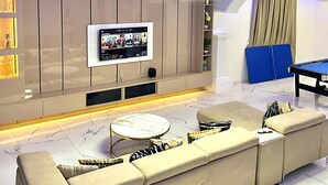 En moderne stue med en stor sofa, et fladskærms-tv og et billardbord.