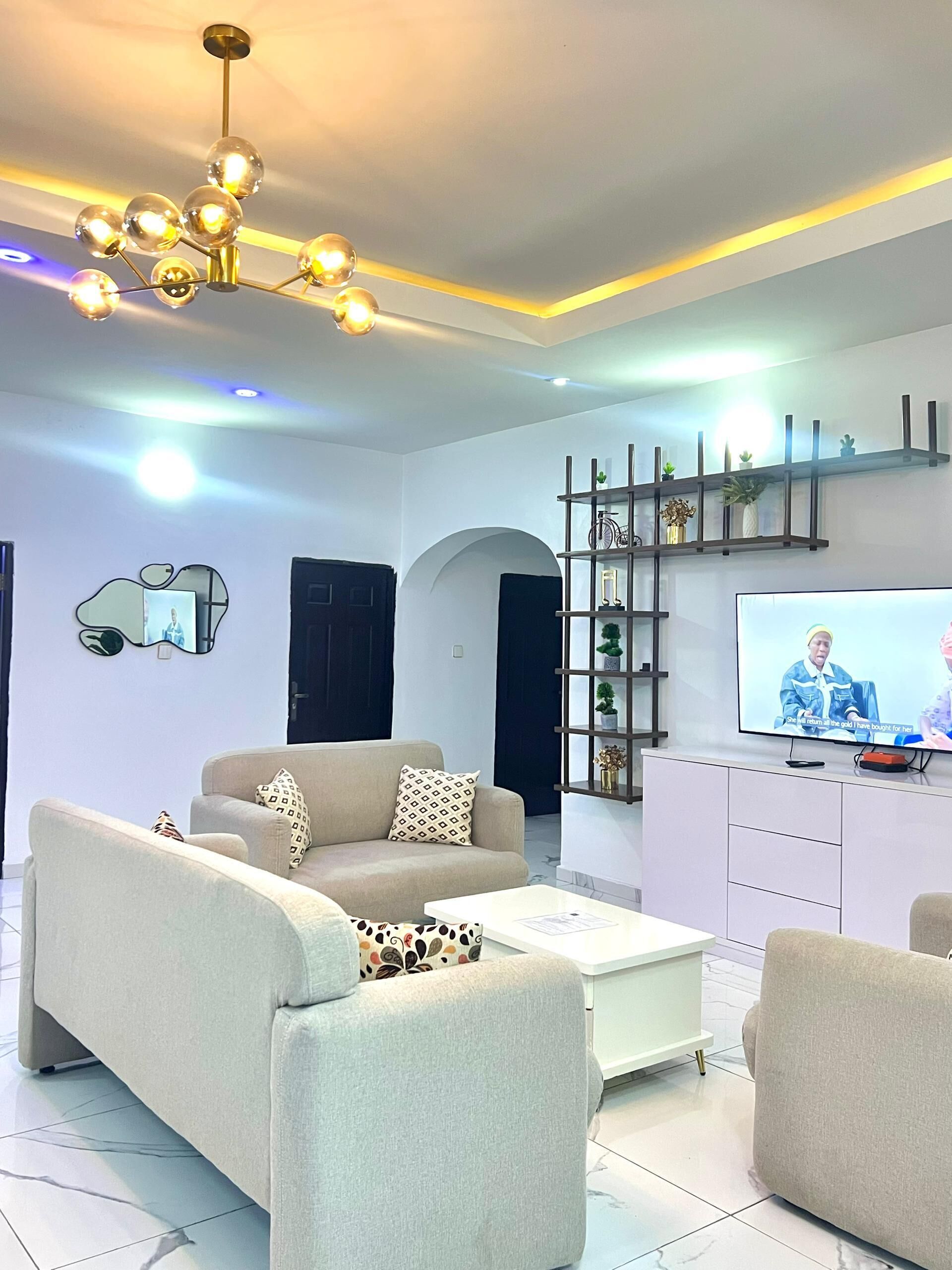 Una sala de estar moderna con sofá, mesa de centro, televisor y estanterías decorativas.