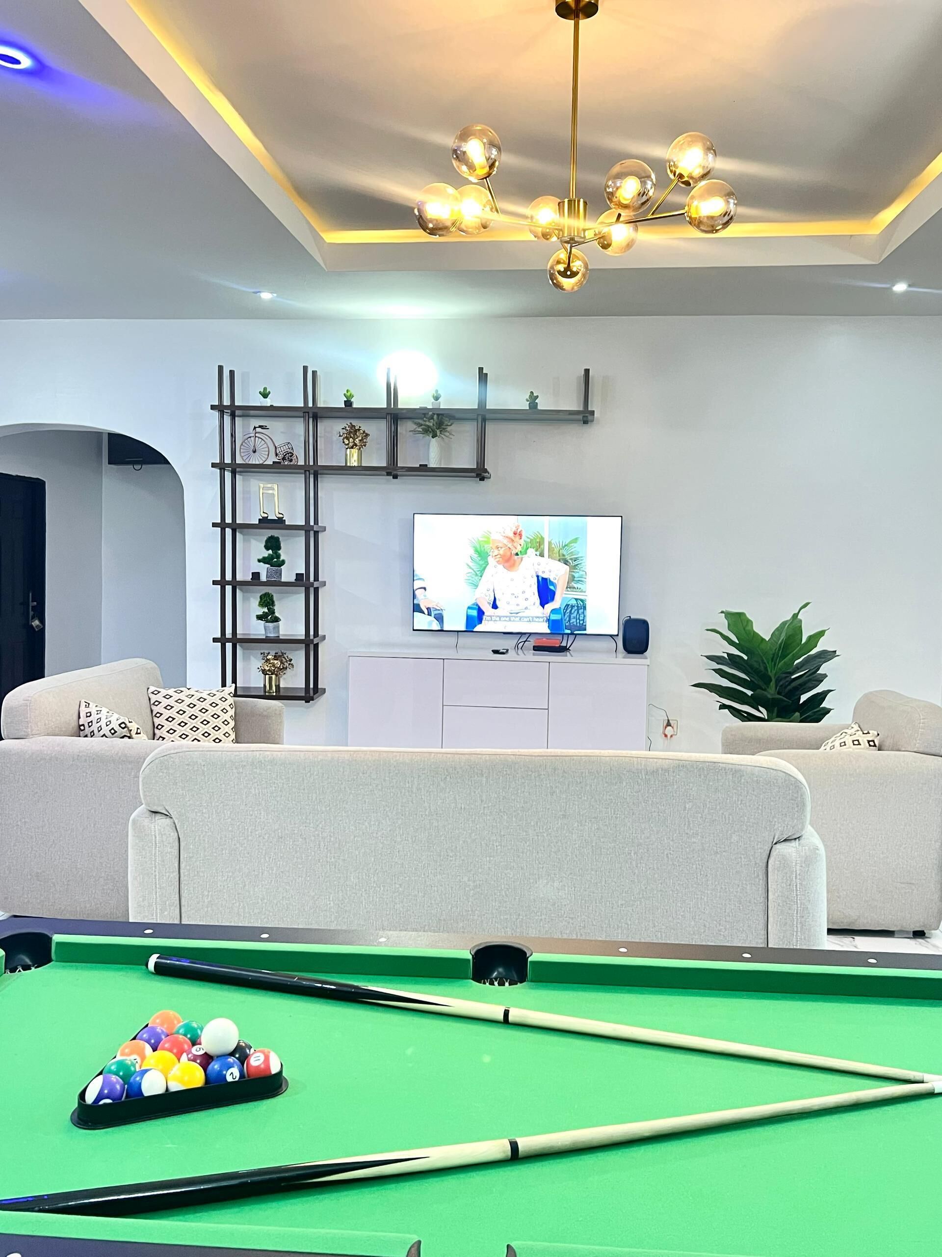 Un soggiorno con tavolo da biliardo, televisione e lampadario.
