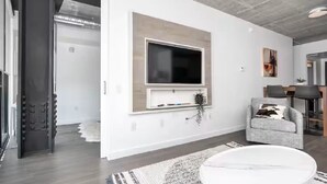 A modern living room with a mounted TV, a grey sofa, and a round coffee table.