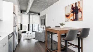 A modern kitchen with a dining area, a sofa, and a large window.