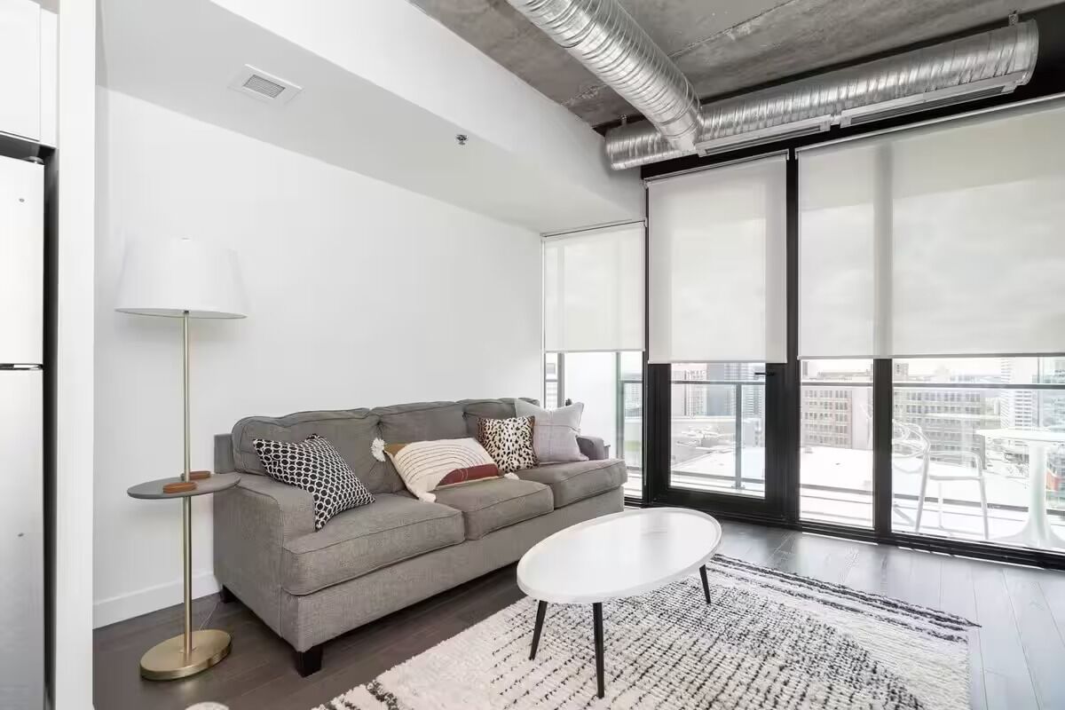 Un salon moderne avec un canapé gris, une table basse blanche et un lampadaire.