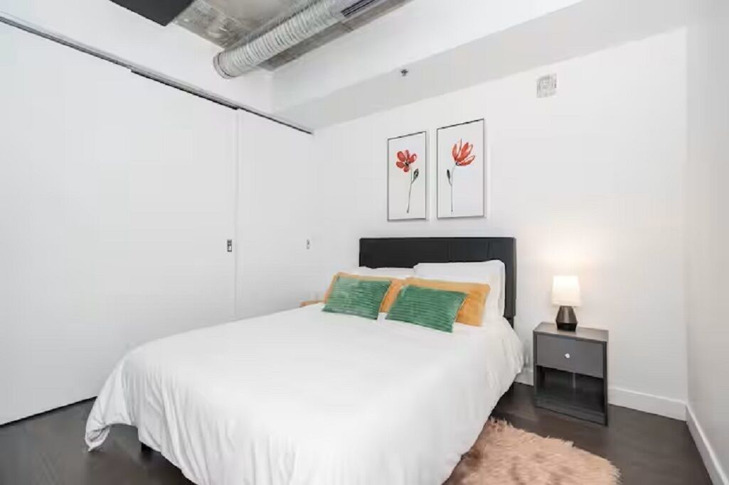 Camera da letto con un letto, un comodino e due opere d'arte appese al muro.
