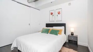 A bedroom with a bed, a nightstand, and two wall-mounted artworks.