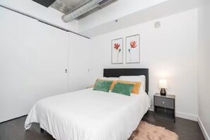 Ein Schlafzimmer mit einem Bett, einem Nachttisch und zwei an der Wand befestigten Kunstwerken.