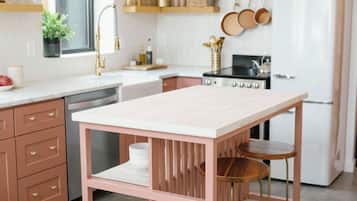 Et køkken med en hvid bordplade, et pink bord og et rustfrit stål køleskab.