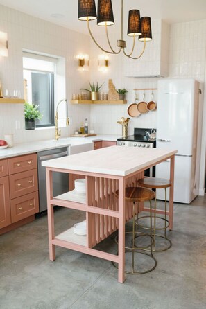 A kitchen with a white countertop, a pink table, and a stainless steel refrigerator. - The Lofts @35th and Clay - Loft A (Garden City)