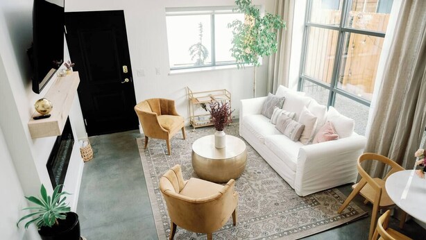 A modern living room with a sofa, two armchairs, a coffee table, and a TV. - The Lofts @35th and Clay - Loft A (Garden City)