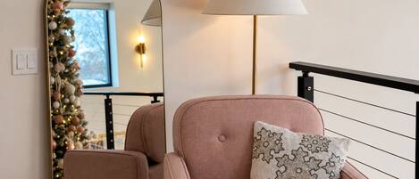 A room with a chair, a lamp, a mirror, and a Christmas tree.