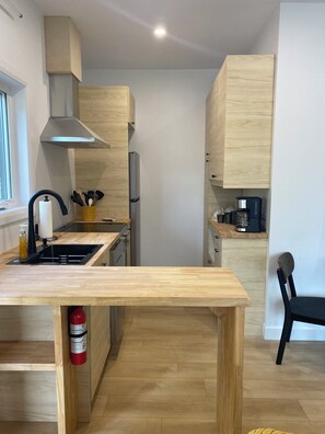 A modern kitchen with wooden cabinets, a stainless steel range hood, a built-in oven, and a coffee maker.