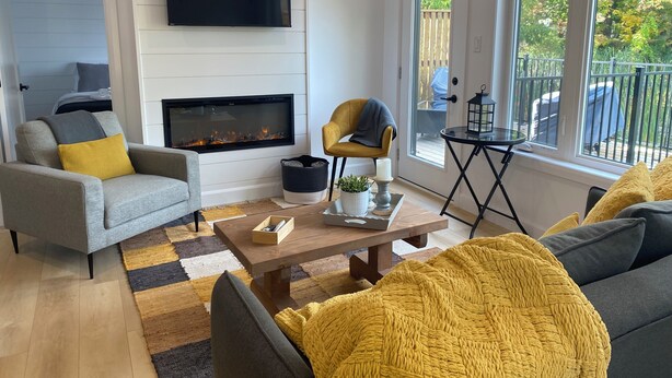 Un salon moderne avec une cheminée, un canapé, une table basse et un téléviseur fixé au mur.