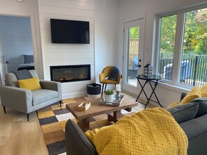 Un salon moderne avec une cheminée, un canapé, une table basse et un téléviseur fixé au mur.