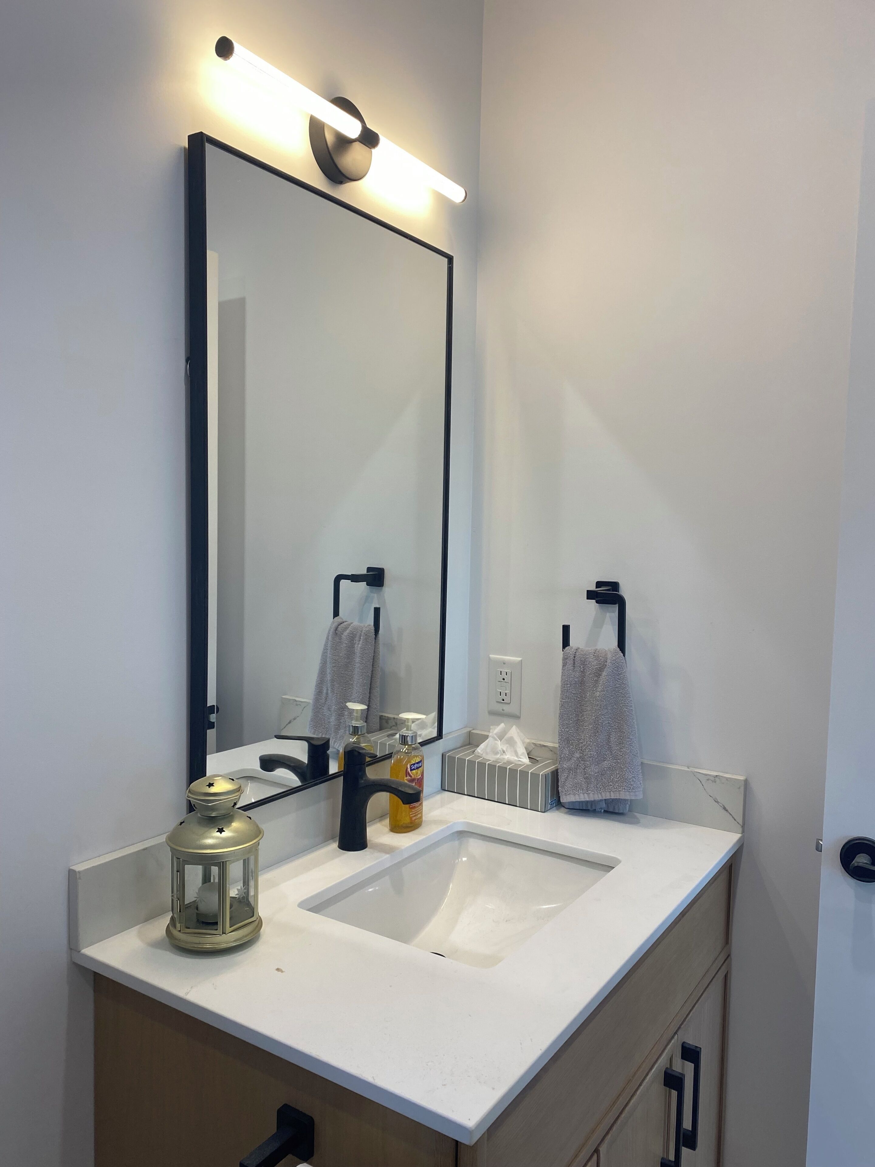 Een moderne badkamer met een grote spiegel, een wit aanrecht en een enkele wastafel.