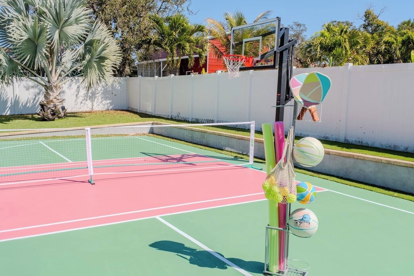 Uma quadra de tênis ao ar livre com rede, aro de basquete e rede de vôlei.