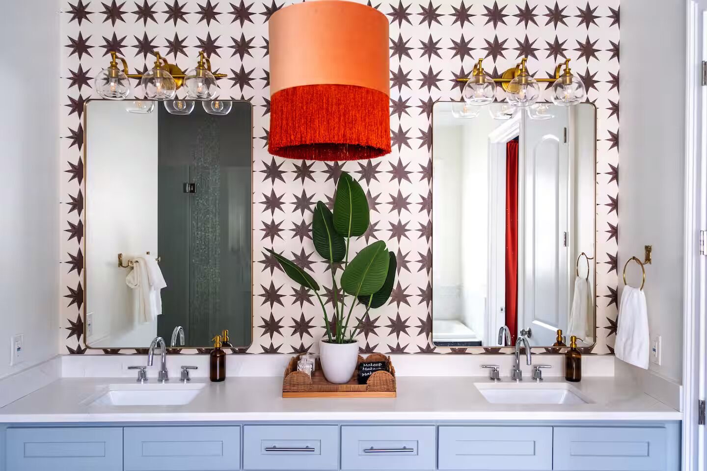 Een badkamer met twee wasbakken, een grote spiegel, een rode accentlamp en een muur met sterenpatroon.