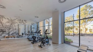 A spacious gym with exercise equipment, large windows, and a mural on the wall. - Apartamento Malaga Towers - DolmenGroup (Málaga)