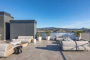 A rooftop terrace with modern outdoor furniture, potted plants, and a cityscape view. - Málaga 1BR · Gym & Coworking · Lift & AC (Málaga)