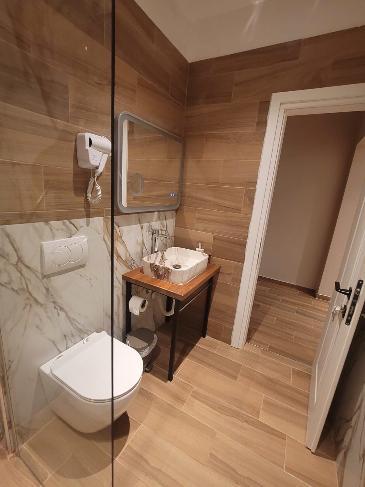 A bathroom with a toilet, a sink, a mirror, and a towel dispenser.