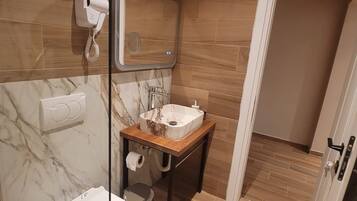 A bathroom with a toilet, a sink, a mirror, and a towel dispenser.