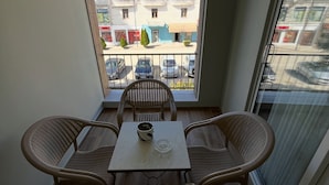 A balcony with wicker furniture, a table, and a potted plant.