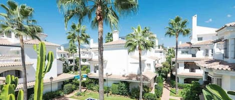 A resort with white buildings, palm trees, and a pool area.