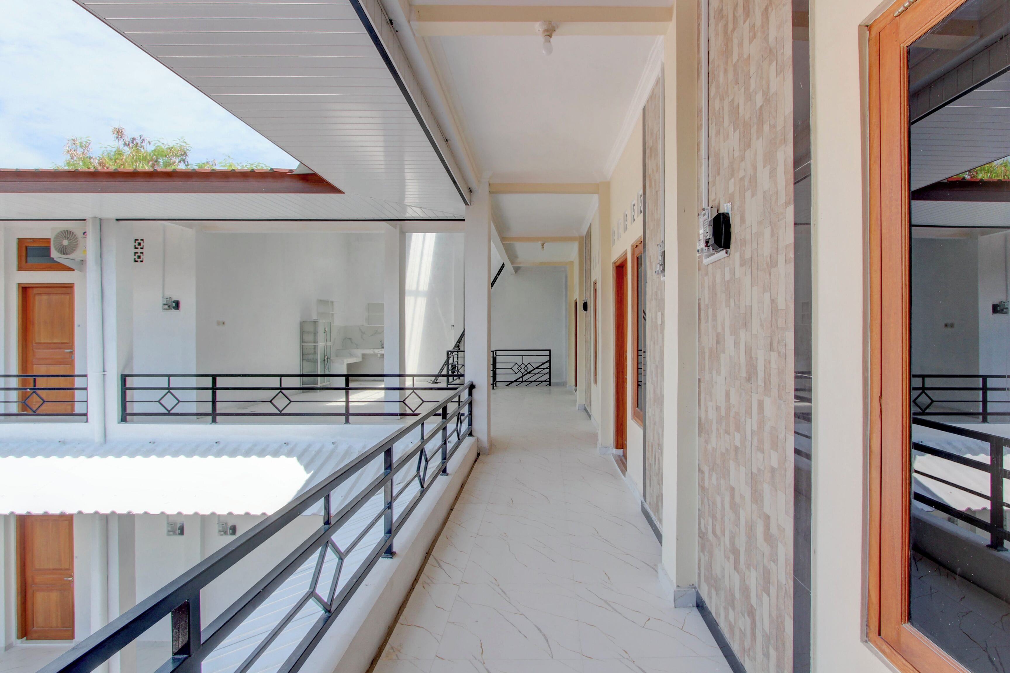 Un corridoio con un balcone, una porta in legno e un muro piastrellato.