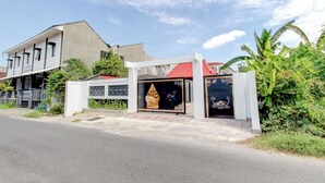 Un bâtiment à deux étages, doté d’un toit rouge, d’une entrée fermée par un portail et d’une grande porte décorative.