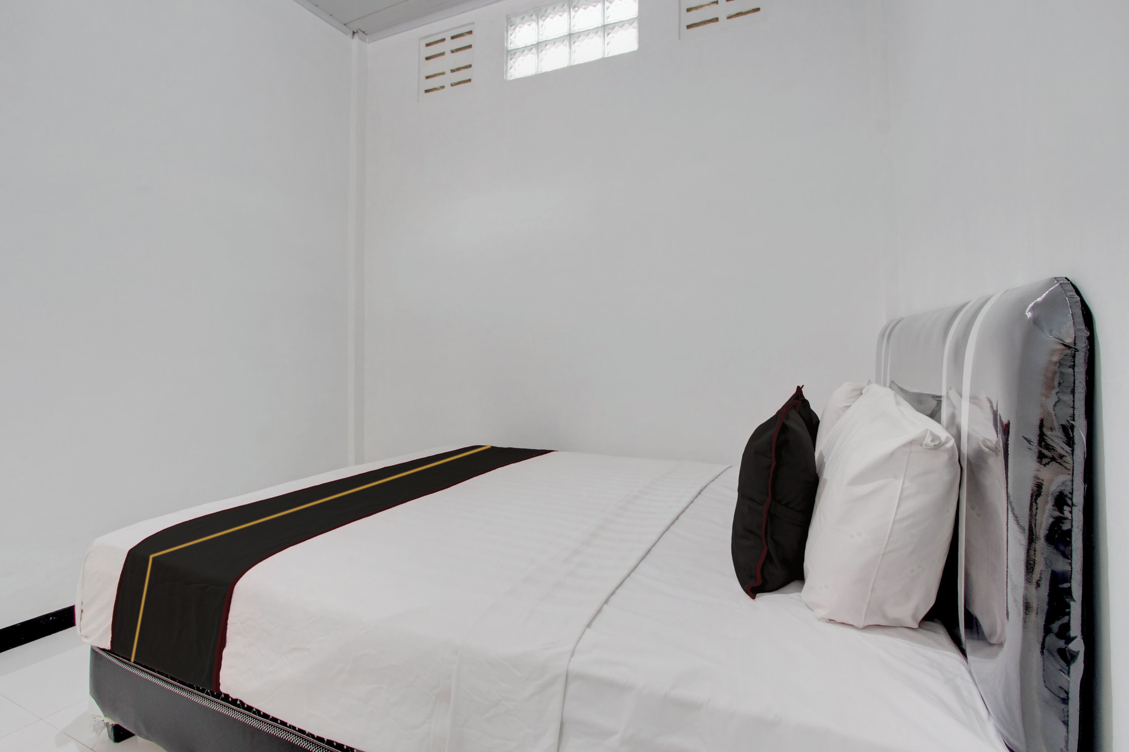 A bed with a white mattress, black and yellow bedspread, and two pillows.