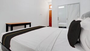Une chambre d’hôtel comprenant un lit, une petite table, une armoire et un appareil de climatisation.