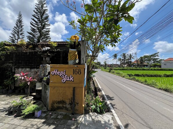 A roadside sign with 'Hepi Yuk' and the number 168, surrounded by greenery and a clear sky. - Hotel O near Plaza Ambarukmo formerly (Banguntapan)
