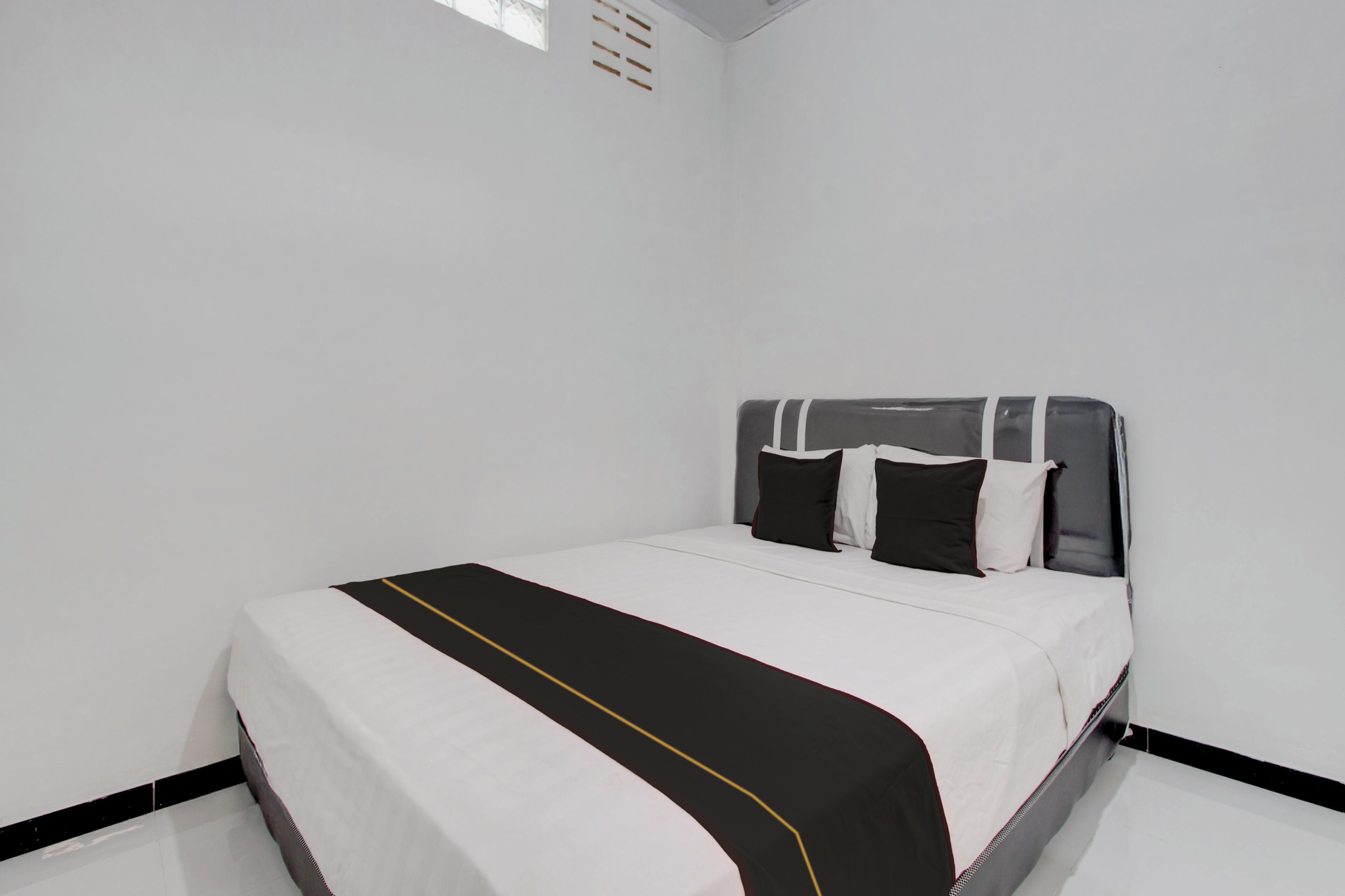 A single bed with a white and black bedspread, two pillows, and a headboard with a striped design.