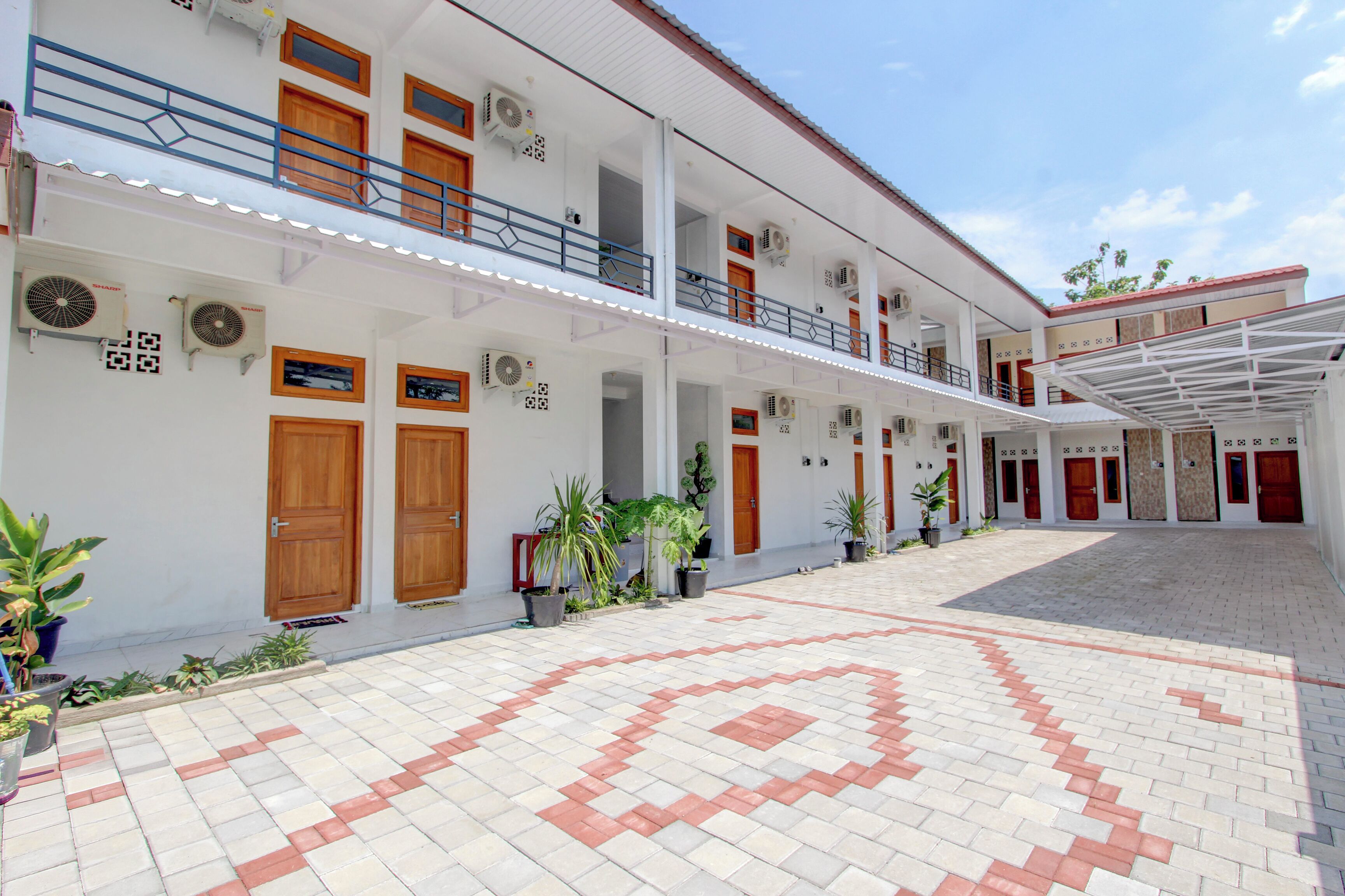 A multi-story hotel with a central courtyard, potted plants, and a patterned floor.
