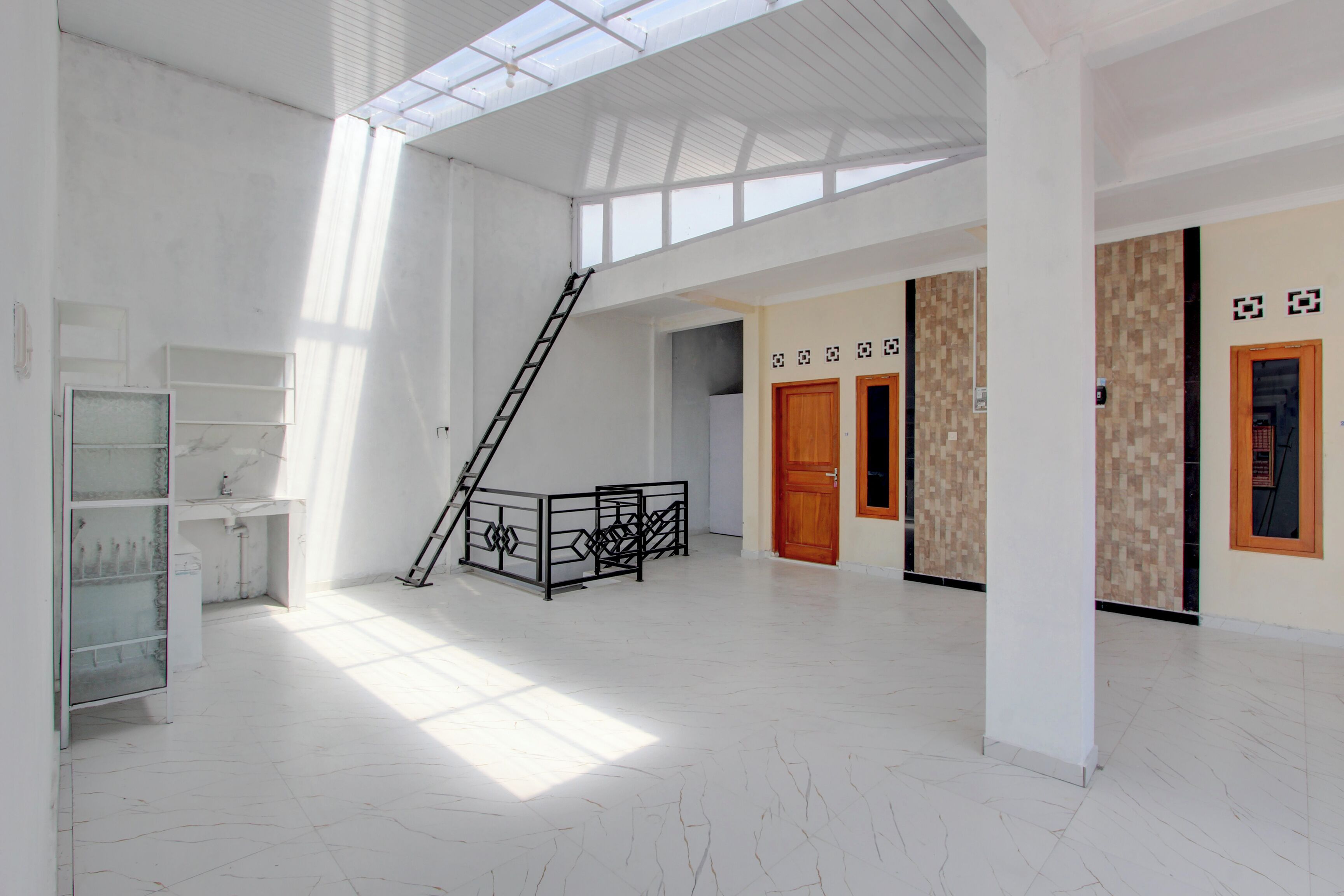 Un ambiente spazioso con soffitto alto, una scala e un pannello di vetro.
