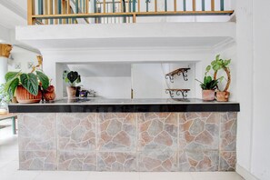 A kitchen with a stone backsplash, a wooden countertop, and potted plants. - Hotel O near Plaza Ambarukmo formerly (Banguntapan)
