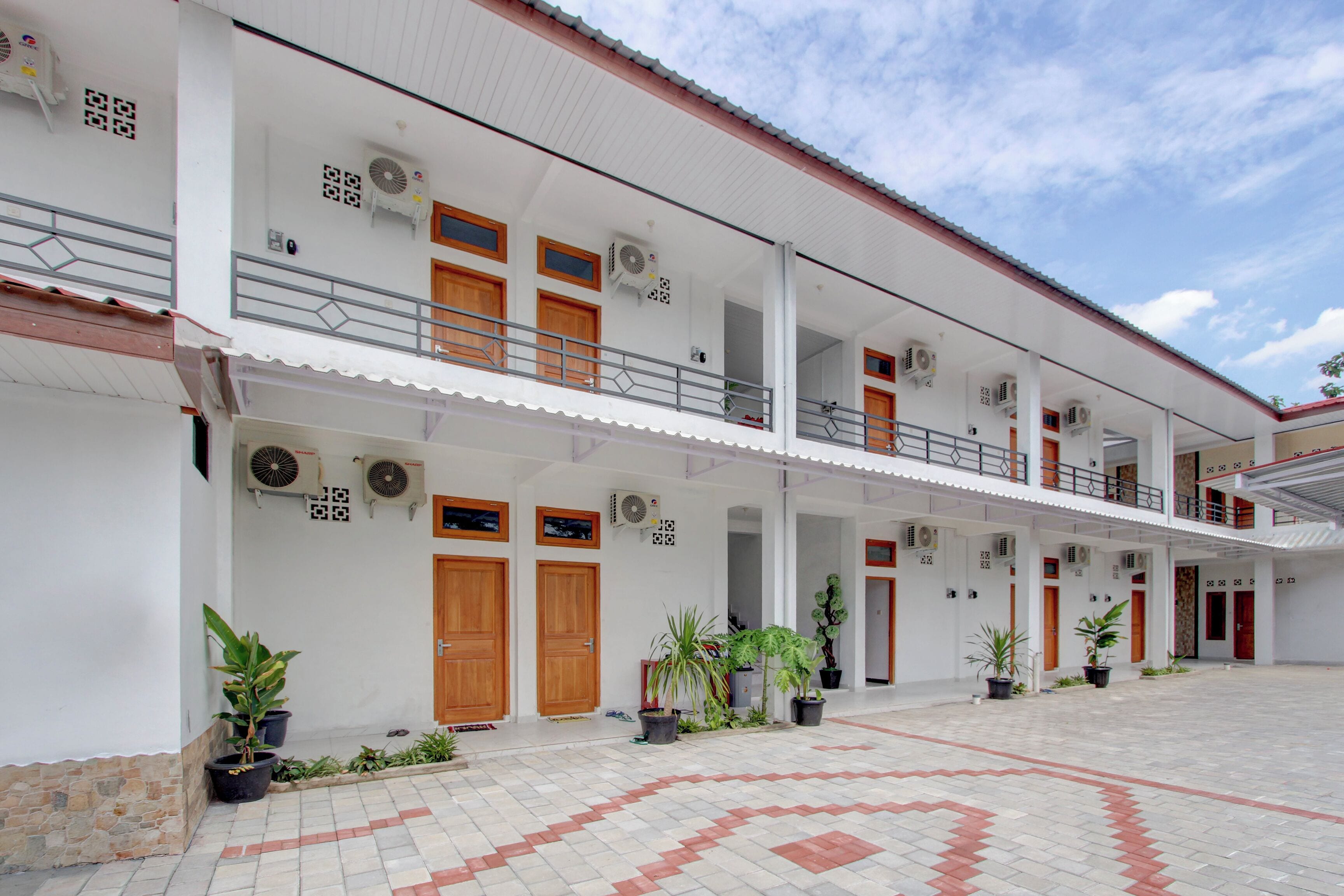 A multi-story building with balconies, potted plants, and air conditioning units.