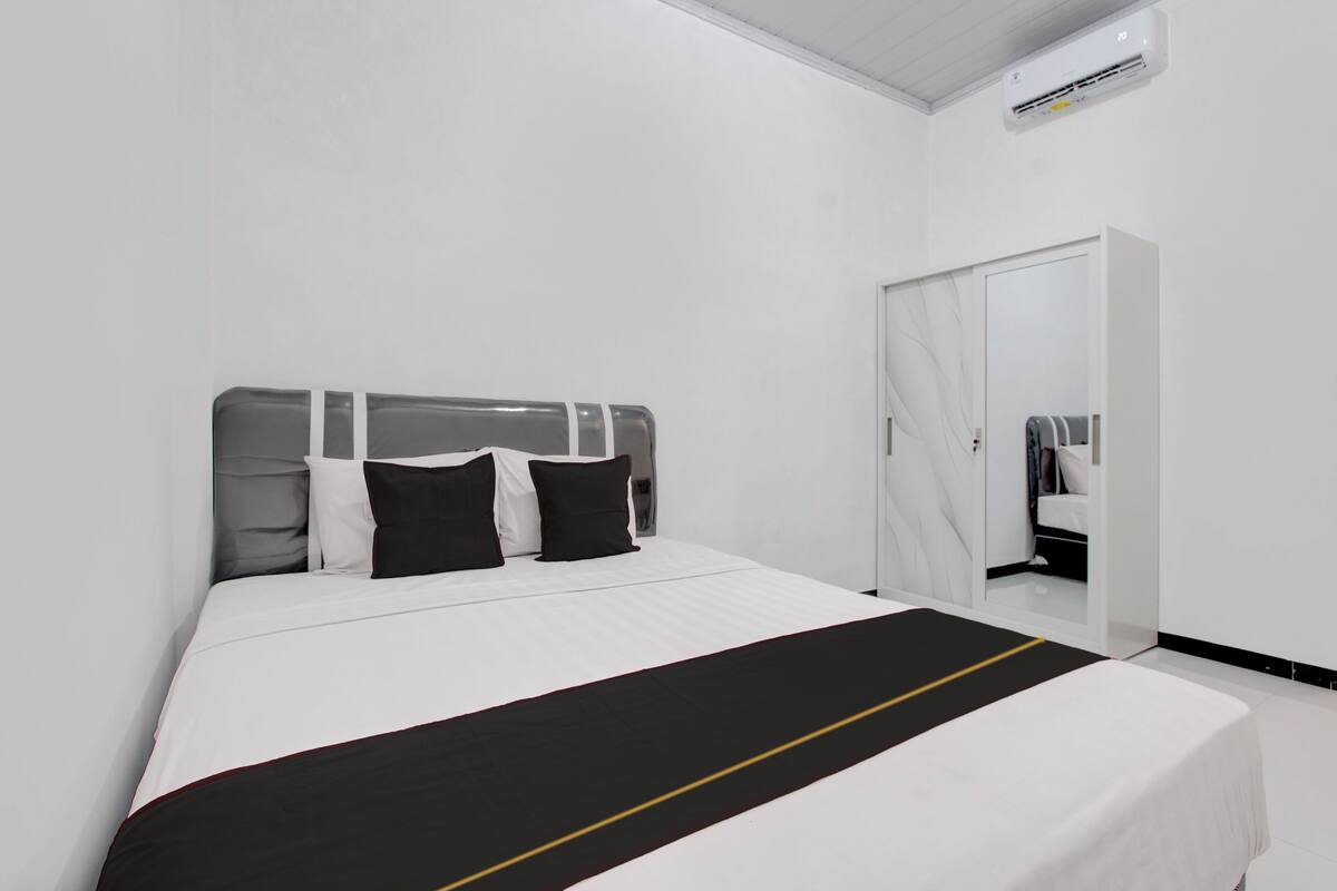 A modern hotel room with a neatly made bed, a wardrobe, and a mirror.