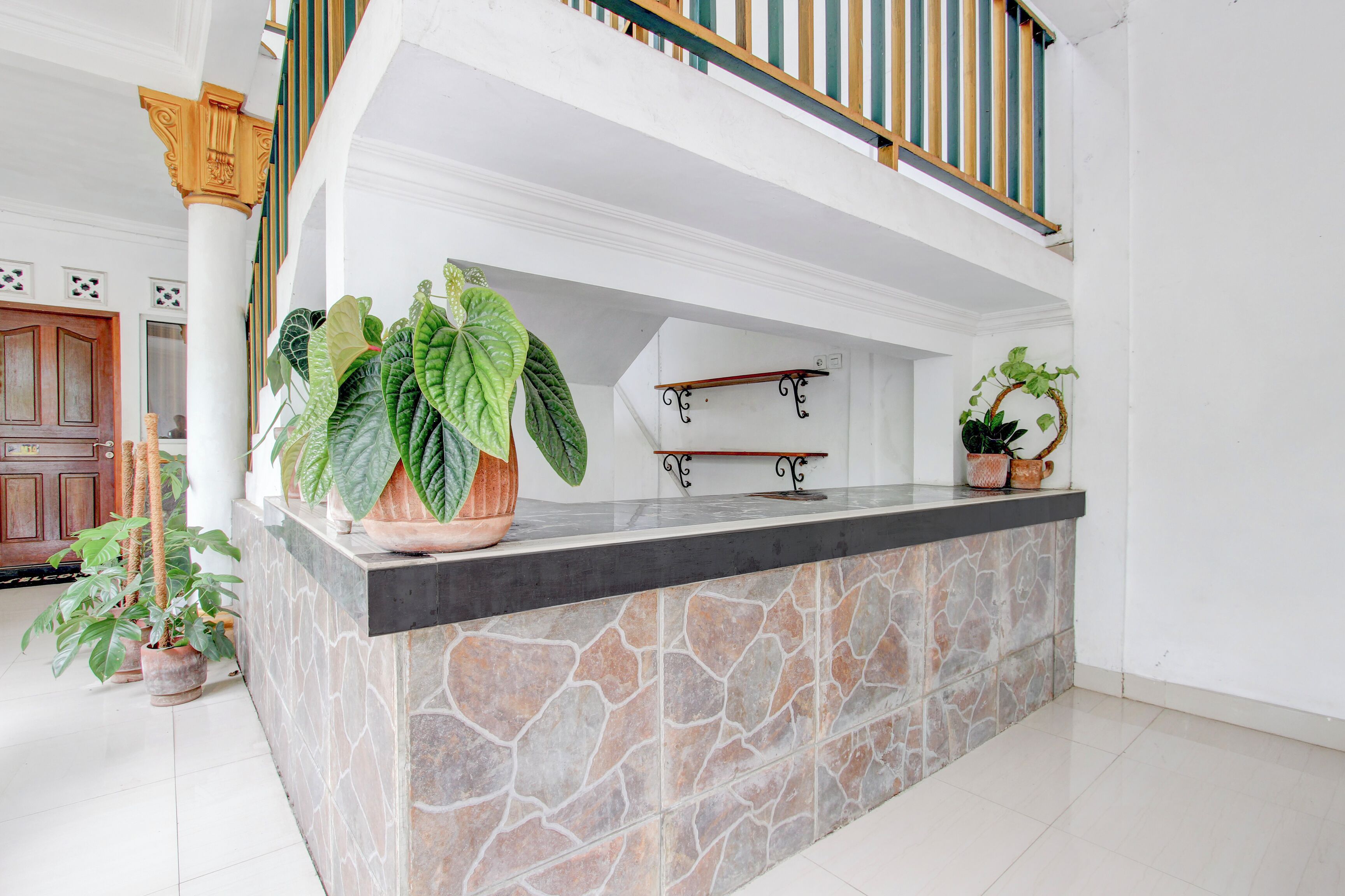 A stone-tiled island bar with a black countertop, surrounded by white walls and a wooden staircase with a green and yellow railing.