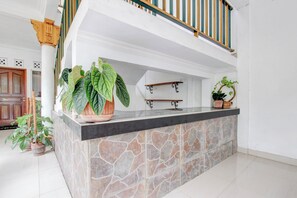 Una barra isla con suelo de piedra y encimera negra, rodeada de paredes blancas y una escalera de madera con barandilla verde y amarilla.