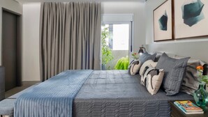 A modern bedroom with a large bed, a bedside table with a book, and a window with curtains. - Flat de 100m2 com Serviço de Camareira (Sao Paulo)